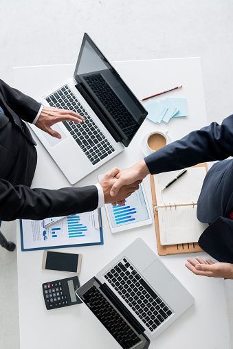 Business professionals collaborating with handshake and documents